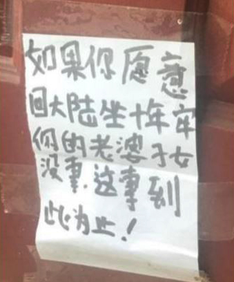 A white piece of paper with Chinese writing posted on a door.
