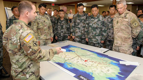 US and PLA military members gathered around a table looking at a map of China