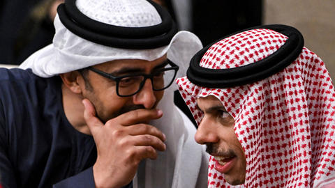 Two Middle Eastern me leaning in toward each other and whispering.