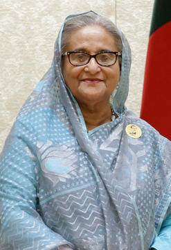Headshot of older Bangladeshi woman smiling and wearing a blue and silver sari wrap.