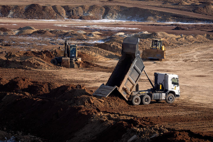 Constructions trucks in an open pit mine in a canyon.