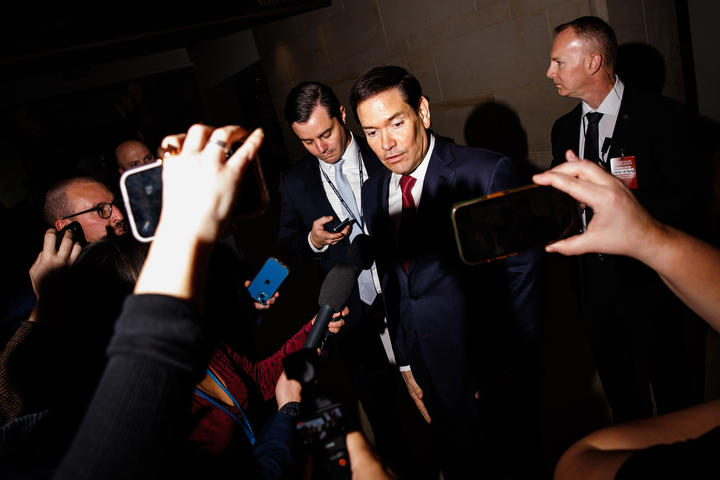 Secretary of State Marco Rubio answers reporters' questions with phones and microphones in his face. 