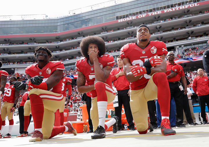 Eli Harold, quarterback Colin Kaepernick and safety Eric Reid kneel during the national anthem before an NFL football game against the Dallas Cowboys in Santa Clara, California.