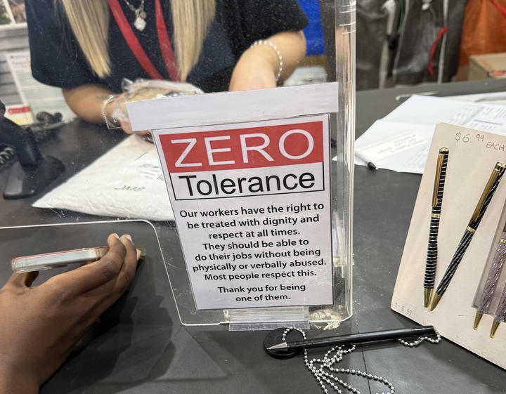 Close-up of a sign on an acrylic barrier between cashier and customer that reads "ZERO Tolerance" and includes text about the respect workers require.