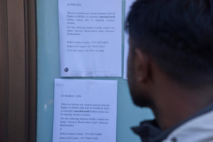 The back profile of a person looking at papers tacked to the wall, showing flight disruptions.