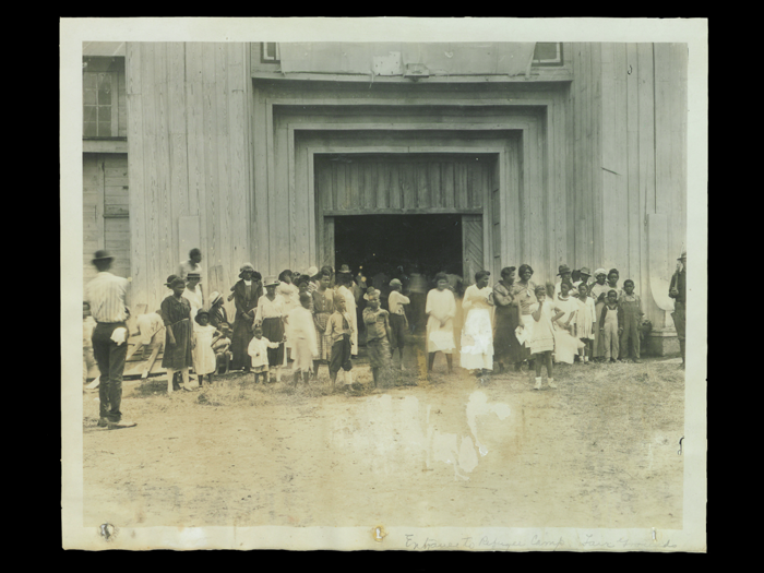 Black folks standing in front of a refugee camp at the local fairgrounds