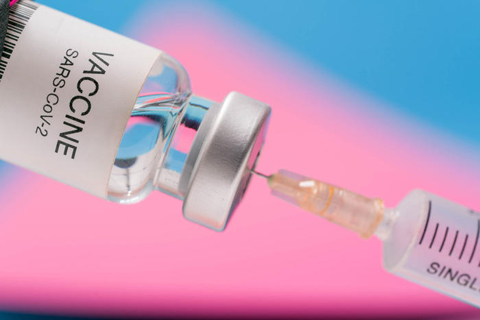 Vaccine vial with syringe isolated over blue background