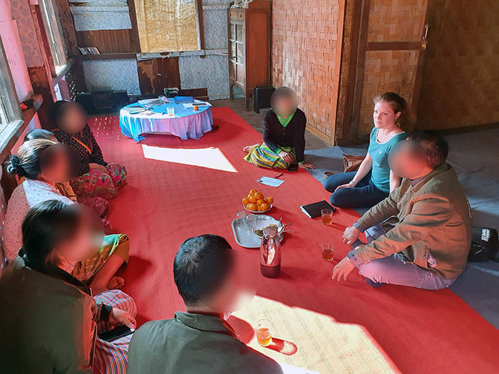 Annette Idler in a focus group in Myanmar with women whose sons or brothers were recruited by armed groups. All participants are sitting in a circle on a red rug on the floor.