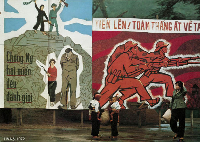 Vietnamese civilians gather in front of propaganda posters in downtown Hanoi, circa 1972.