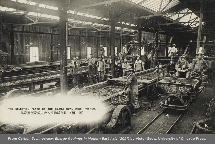 Old photograph of about 15 miners posing for a picture inside a coal mine building