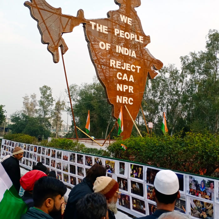 Image of people looking at a photo wall curated by the youth of Jamia Miliia Islamia University at Shaheen Bagh protests
