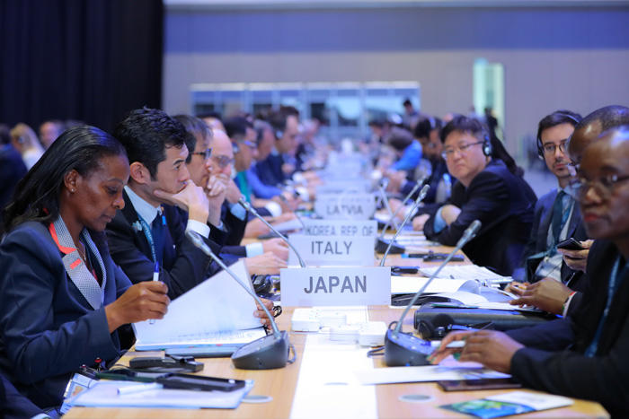 Country representatives sit on either side of a long table at a WTO meeting on climate in 2024.