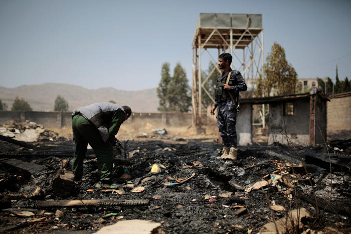 Two Yemeni police officers inspecting the site of the destruction of houses.